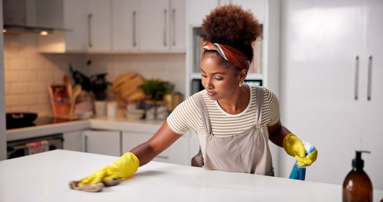 Woman cleaning kitchen counter for hygiene with spray and cloth