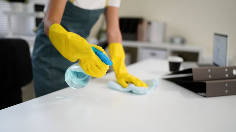 Young woman cleaning table with disinfectant spray and blue cloth promoting hygiene